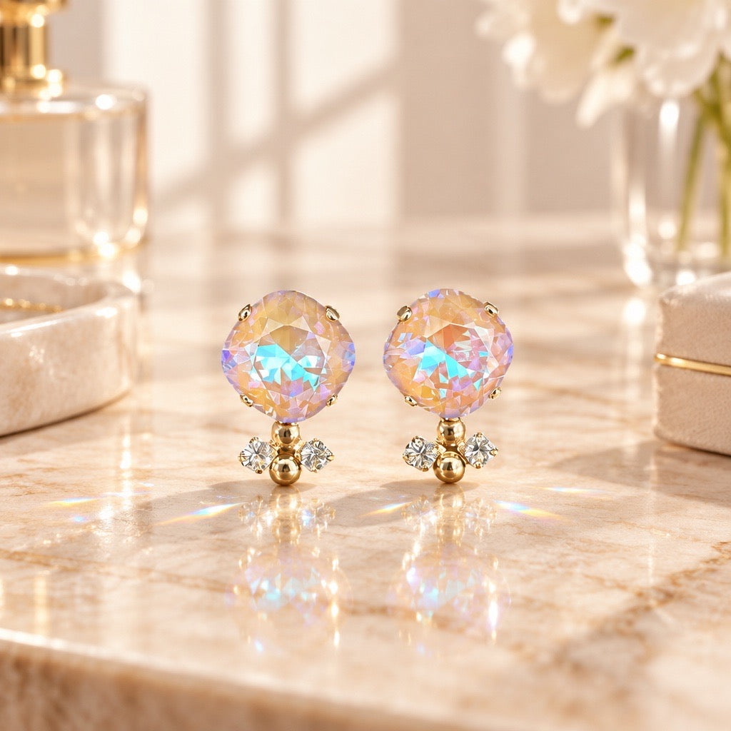 Gold nude aurora oorsteker met iriserende ronde Swarovski steen en drie kleine kristallen in gouden setting op marmeren ondergrond, DAMICE Jewelry